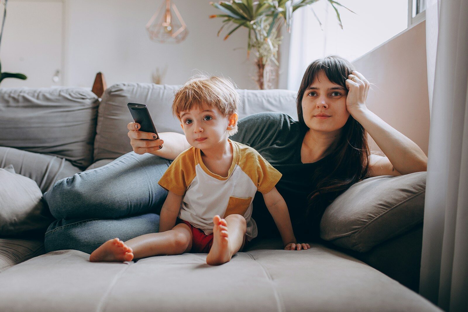 Una mujer y un niño en el sofá mirando una pantalla